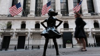 People walk by the Fearless Girl bronze sculpture outside the New York Stock Exchange on April 21, 2023.