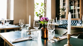 A restaurant table with wine glasses and candles, ready for customers to sit down for lunch.