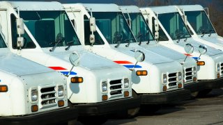 Line of US Postal Service trucks in a parking lot