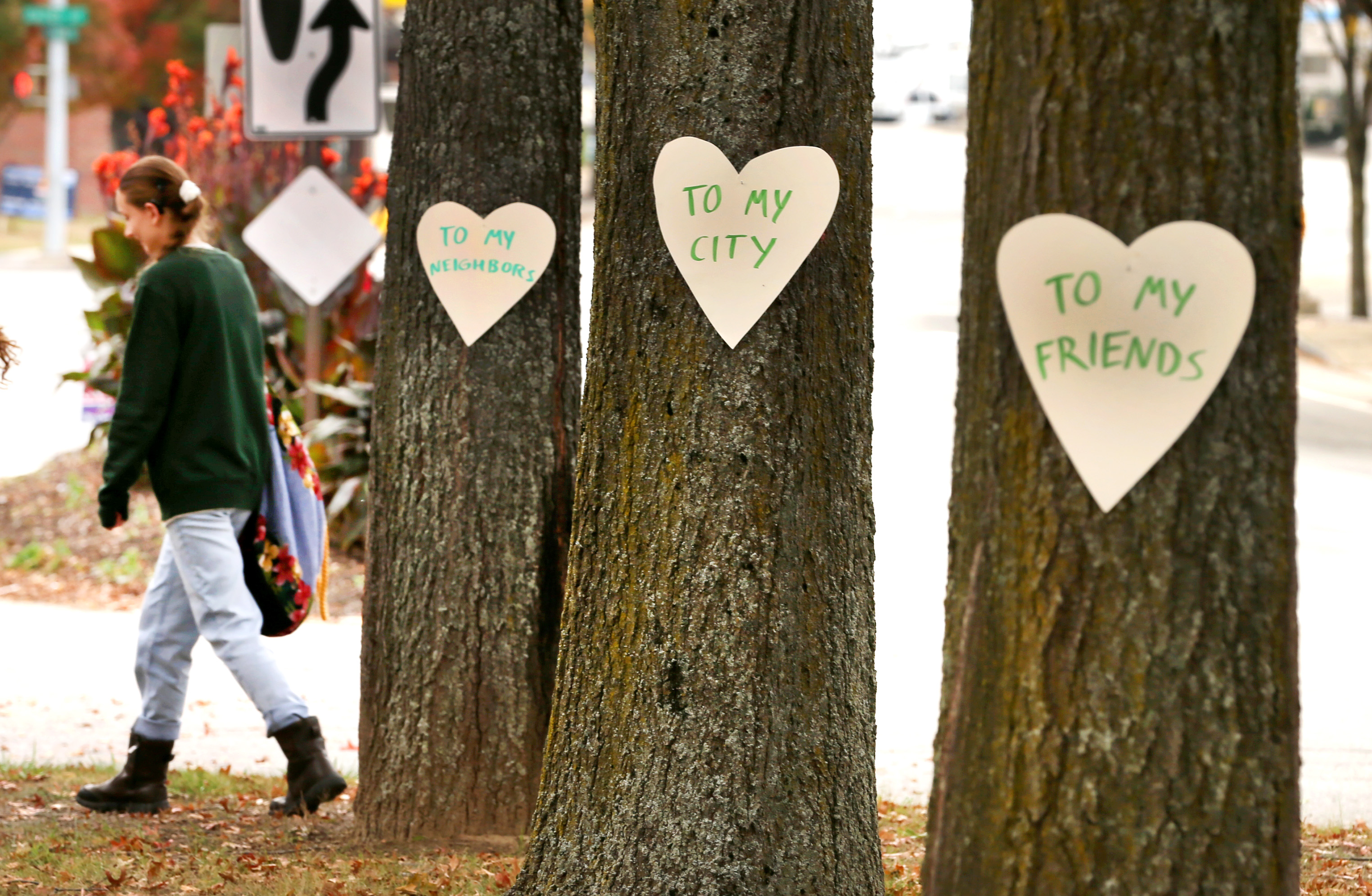 Artist Miia Zellner walks away after nailing hearts she made to trees on Main Street in Lewiston, Maine, the day after mass shootings took place in the city.