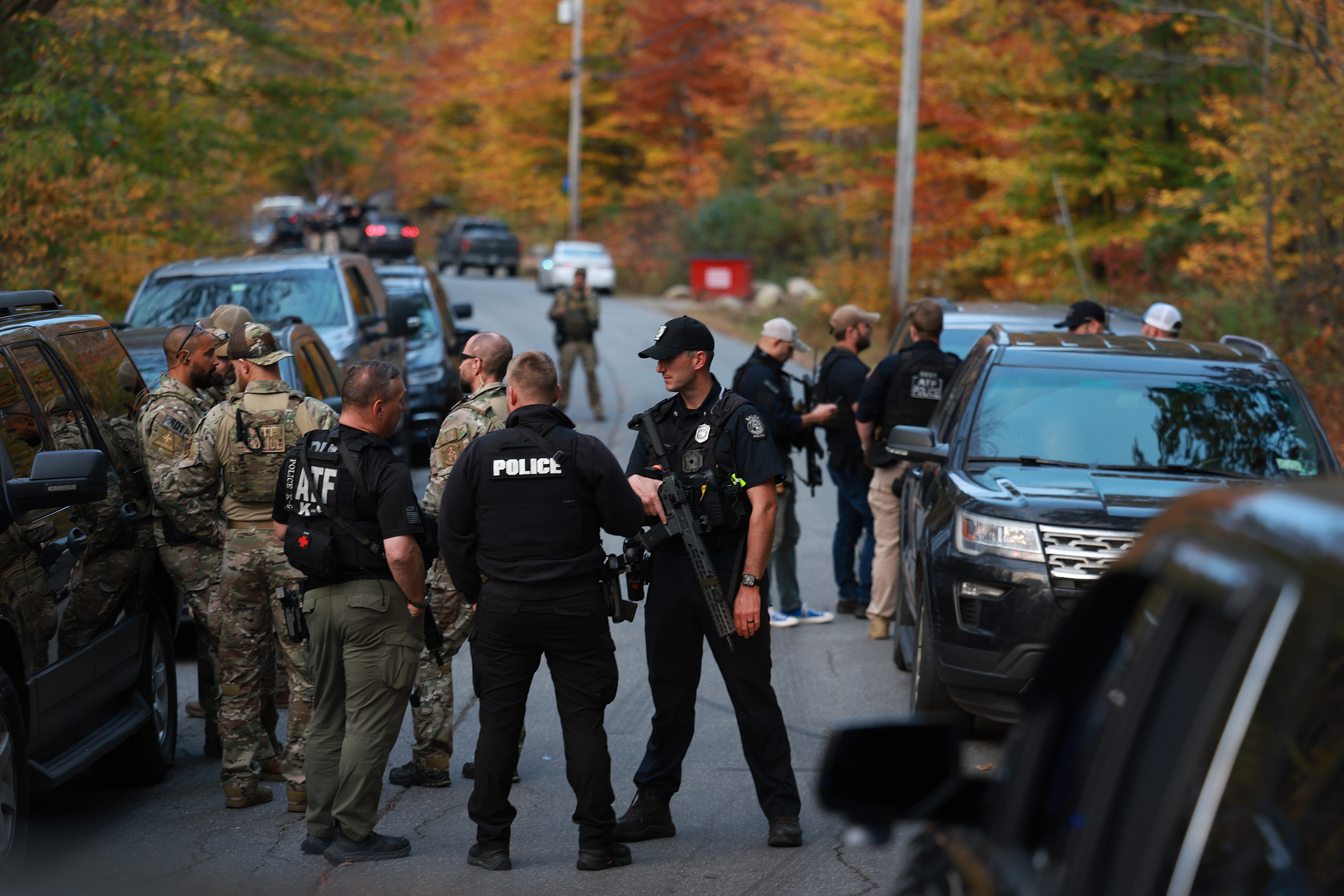 Law enforcement officials gather in the road leading to the Bowdoin, Maine home of the suspect being sought in connection with the mass shootings, Thursday, Oct. 26, 2023.