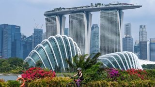 A woman rides her bicycle with the Marina Bay Sands hotel and high-rise buildings in the background in Singapore on Sept. 4, 2023.