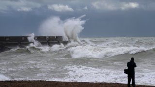 A man takes a photograph as waves crash over the harbour wall as Storm Ciaran brings high winds and heavy rain along the south coast of England, in Brighton, England, Thursday, Nov. 2, 2023. Winds up to 180 kilometers per hour (108 mph) slammed France’s Atlantic coast overnight as Storm Ciaran lashed countries around western Europe, uprooting trees, blowing out windows and leaving 1.2 million French households without electricity Thursday. Strong winds and rain also battered southern England and the Channel Islands, where gusts of more than 160 kph (100 mph) were reported. (AP Photo/Kin Cheung)