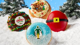 Four Elf-themed Krispy Kreme donuts on a bed of snow.