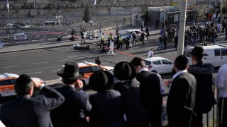 People look at Israeli police officers and volunteers from the Zaka rescue service work at the shooting attack in Jerusalem, Thursday, Nov. 30, 2023. The shooting death of an Israeli man who raced to confront Palestinian attackers has raised questions about the use of excessive force among Israeli security forces and the public. The man's shooting mirrors previous incidents where Israeli security forces or civilians have opened fire on attackers who no longer appear to pose a threat or on suspected assailants or unarmed civilians.