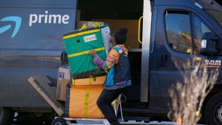 An Amazon Prime delivery person lifts packages while making a stop at an apartment building on Tuesday, Nov. 28, 2023, in Denver.