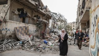 Residents inspect the rubble of the building following an Israeli attack on house