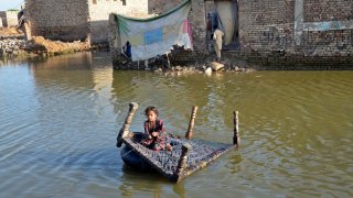 A girl sits on a cot as she crosses a flooded street in Pakistan on October 4, 2022. A record 32.6 million internal displacements were associated with disasters in 2022 — more than the 28.3 million with conflict and violence, according to the Internal Displacement Monitoring Centre.