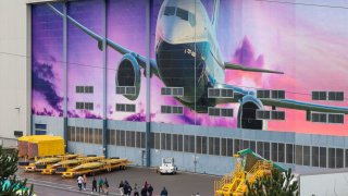 Boeing workers are pictured exiting a gate below an image of a Boeing 737-800 aircraft as Boeing’s 737 factory teams hold the first day of a “Quality Stand Down” for the 737 program in Renton, Washington on January 25, 2024.