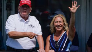 FILE – Rep. Marjorie Taylor Greene, R-Ga., waves while former President Donald Trump points to her while they look over the 16th tee during the second round of the Bedminster Invitational LIV Golf tournament, July 30, 2022, in Bedminster, N.J.