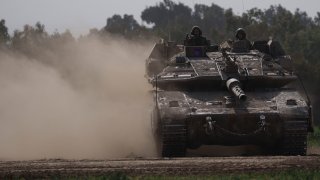 Israeli soldiers move on the top of a tank near the Israeli-Gaza border.