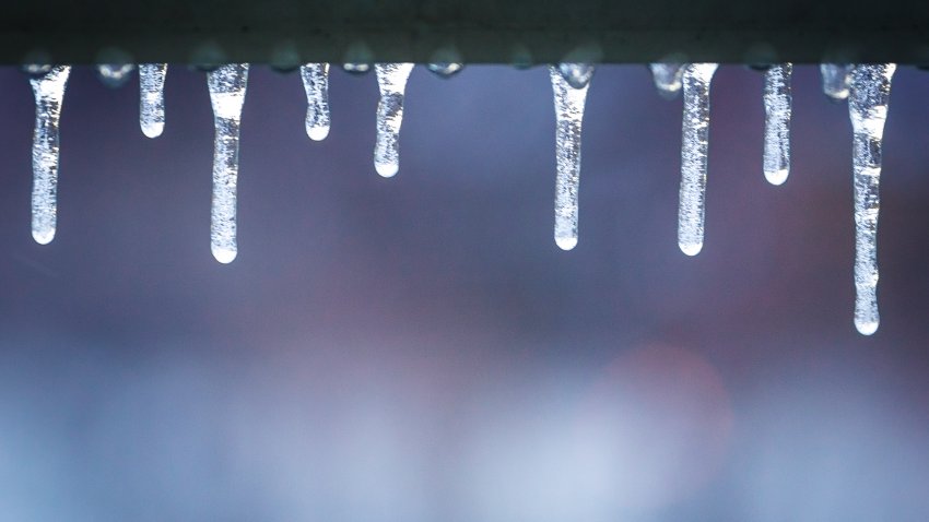 Multiple icicles hanging off a railing.  The background is not in focus.