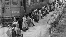 In this photo provided by the National Archives, Japanese Americans from San Pedro, Calif., arrive at the Santa Anita Assembly Center in Arcadia, Calif., on April 5, 1942. People were temporarily housed at this center at the Santa Anita race track before being moved inland to internment camps during World War II. (Clem Albers/War Relocation Authority/National Archives via AP)