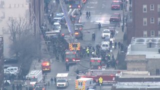 Dozens of Chicago firefighters stand on the street near a 10-story high-rise in South Shore. The view is from far away, captured by the Sky 5 helicopter.