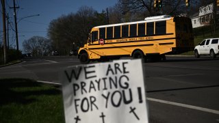 A school bus drives past a sign in support for victims of a shooting at the Covenant School campus, in Nashville.