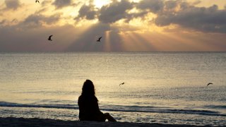 A woman meditates on the beach in Miami Beach, Fla.