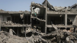 Palestinians look at the destruction after an Israeli strike on a residential building