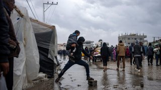 Palestinians displaced by the Israeli air and ground offensive on the Gaza Strip walk through a makeshift tent camp in Rafah on Jan. 27, 2024. The tent camps stretch for more than 16 kilometers (10 miles) along Gaza’s coast, filling the beach and sprawling into empty lots, fields and town streets.