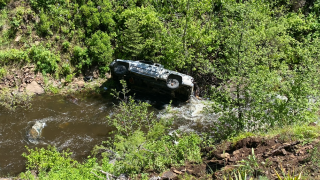 A truck on its side in a ravine.