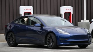 A dog looks out the window from a Tesla electric vehicle charging at a Tesla Supercharger location in Santa Monica, California, on May 15, 2024.