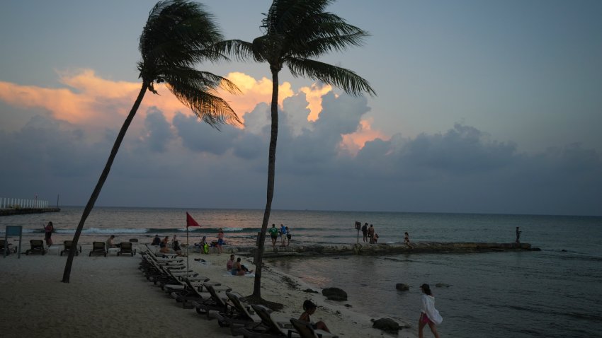 People lounge on the beach as the sun sets ahead of Hurricane Beryl's expected arrival