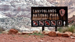 FILE – A sign for Canyonlands National Park is seen, May 6, 2003, in Moab, Utah. Three hikers died over the weekend in suspected heat-related incidents at parks in Utah, including a father and daughter who got lost on a strenuous hike in Canyonlands National Park in triple-digit temperatures. The Canyonlands hikers died Friday, July 12, 2024, while a third deceased hiker was found in Utah’s Snow Canyon State Park.