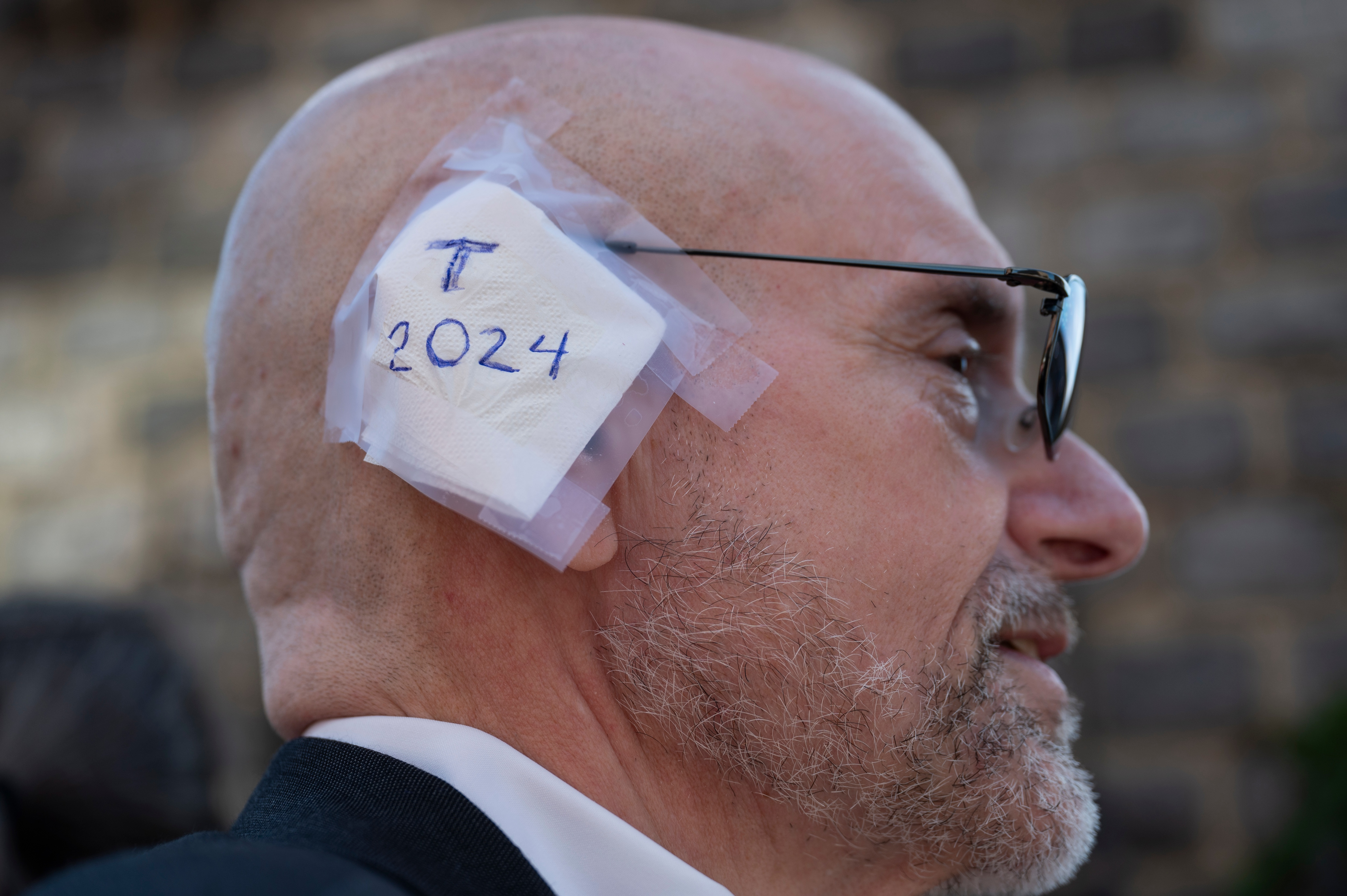 A delegate wears an imitation ear bandage during the Republican National Convention (RNC) outside the Fiserv Forum in Milwaukee, Wisconsin, US, on Wednesday, July 17, 2024. The RNC chairman warned against complacency when his party concludes its official nominating jamboree this week with polls predicting ex-President Donald Trump prevailing over President Joe Biden in the November election. Photographer: Vincent Alban/Bloomberg via Getty Images