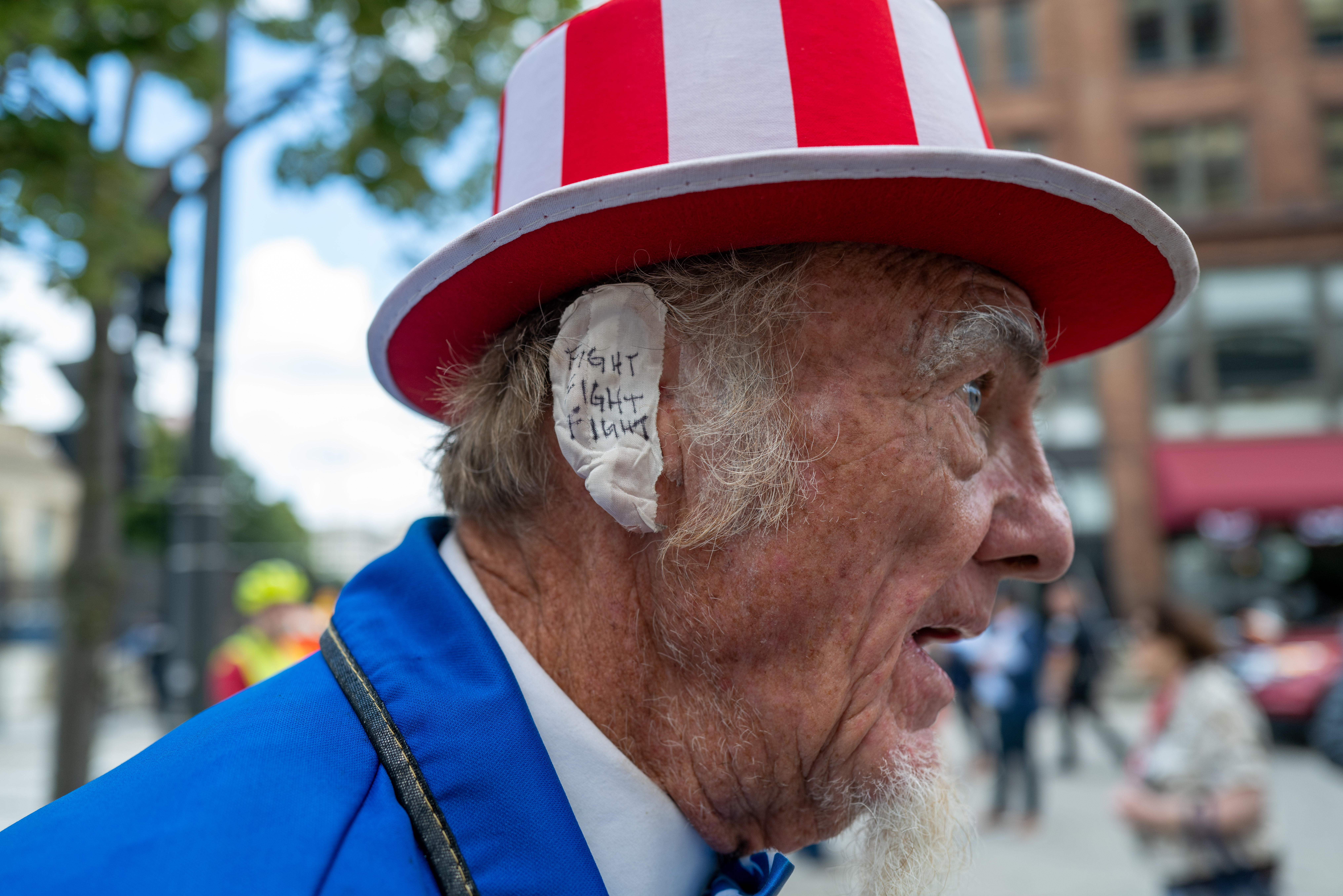 MILWAUKEE, WISCONSIN – JULY 17: A Donald Trump supporter and performer places a bandage over his ear in reference to Trump’s wound at the Republican National Convention (RNC) on the third day of the convention on July 17, 2024 in Milwaukee, Wisconsin. Security throughout downtown Milwaukee remains high following the assassination attempt on former President Donald Trump over the weekend. Thousands of delegates, politicians and the Republican faithful are arriving into the traditionally Democratic city over the next few days for the annual convention which will conclude with former President Donald Trump accepting his party’s presidential nomination. The RNC takes place from July 15-18.  (Photo by Spencer Platt/Getty Images)