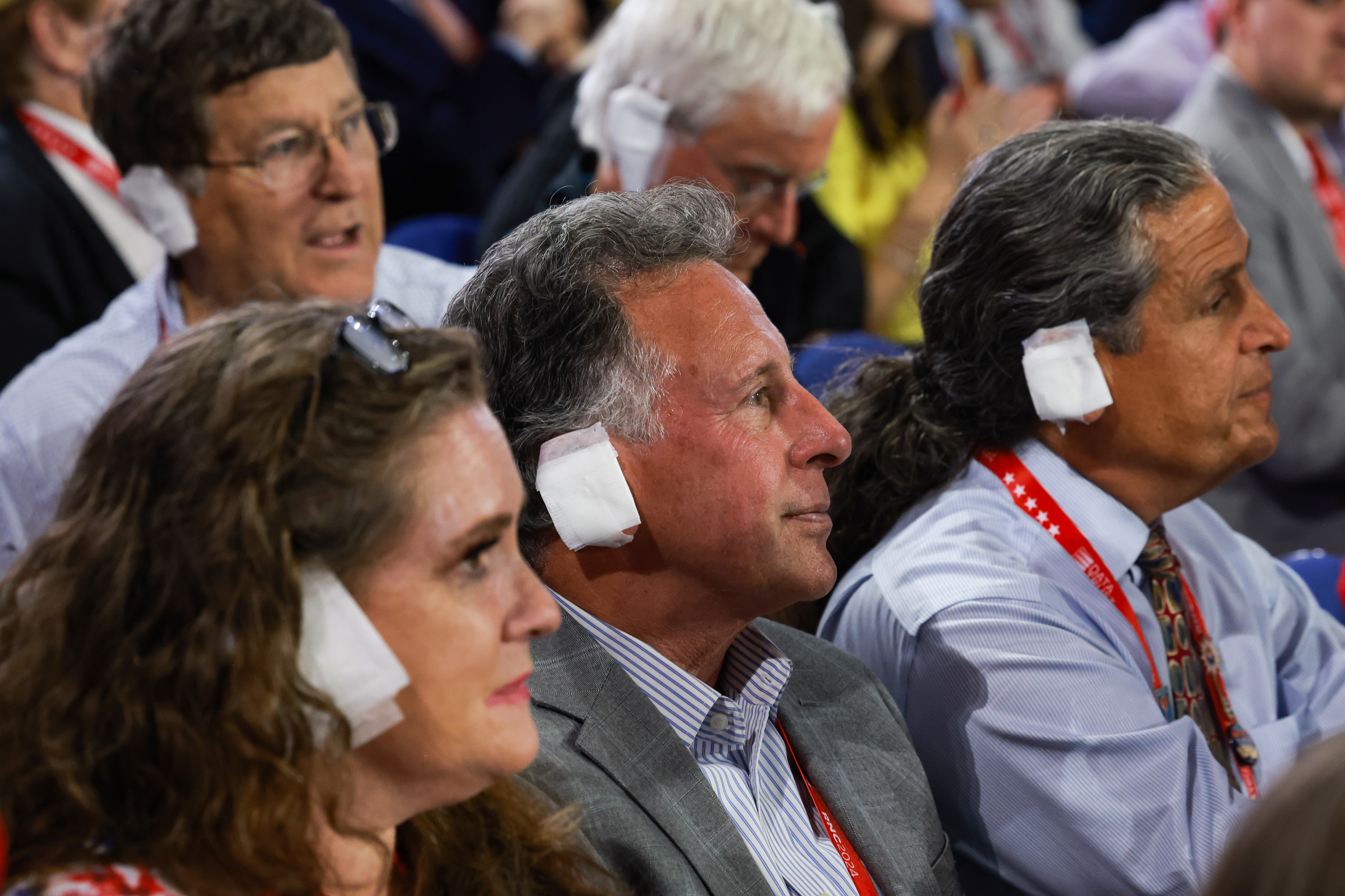 MILWAUKEE, WISCONSIN – JULY 17: People wear “bandages” on their ears as they watch  on the third day of the Republican National Convention at the Fiserv Forum on July 17, 2024 in Milwaukee, Wisconsin. Delegates, politicians, and the Republican faithful are in Milwaukee for the annual convention, concluding with former President Donald Trump accepting his party’s presidential nomination. The RNC takes place from July 15-18.  (Photo by Joe Raedle/Getty Images)