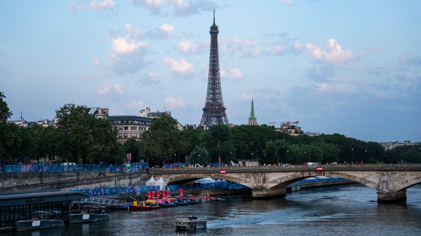 A boat floats down the Seine River at sunrise after the Men's triathlon race was postponed due to Seine pollution and high E.coli levels during the 2024 Summer Olympics, at the Pont Alexandre III bridge in Paris, France, on Tuesday, July 30, 2024.