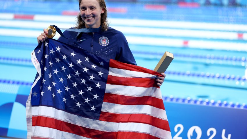 Gold Medalist Katie Ledecky of Team United States poses with the national flag of the United States