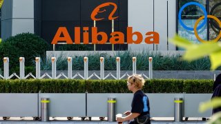 A person seen walking next to the Alibaba’s corporate logo, in front of its office building at Chaoyang Technology Park in Beijing, China.