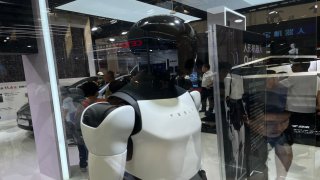 Tesla displays Optimus next to two of its vehicles at the World Robot Conference in Beijing on Aug. 22, 2024.