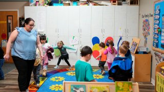 Family Educator Lisa Benson-Nuyen, left, leads her students in a circle as they play music