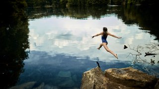 Girl jumping into a lake.