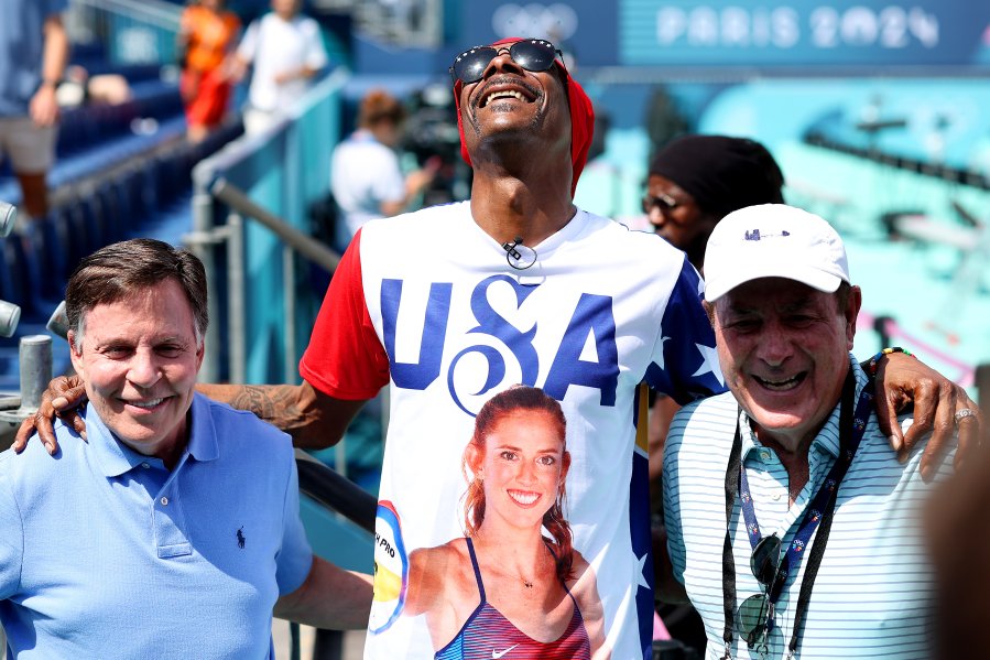 noop Dogg poses for photos with American sportscasters, Bob Costas (L) and Al Michaels at beach volleyball