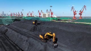 Excavators transfer coal at the coal terminal in China’s eastern Jiangsu province on January 22, 2024.