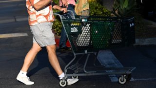 A customer pushes a shopping cart with bags outside of a Whole Foods Market grocery store on August 26, 2024 in El Segundo, California.