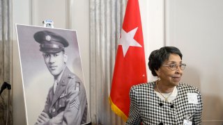 Joann Woodson stands near a portrait of her husband U.S. Army Staff Sgt. Waverly Woodson Jr.