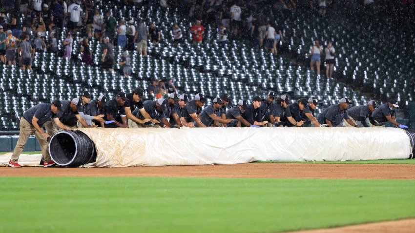 CHICAGO, ILLINOIS – JUNE 24: Grounds crew members cover the field during a rain delay in the seventh inning in the game between the Los Angeles Dodgers and the Chicago White Sox at Guaranteed Rate Field on June 24, 2024 in Chicago, Illinois. (Photo by Justin Casterline/Getty Images)