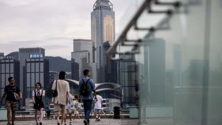 People walk along a promenade next to Victoria harbour in Hong Kong on August 31, 2023, a day before the arrival of Typhoon Saola. (Photo by ISAAC LAWRENCE / AFP) (Photo by ISAAC LAWRENCE/AFP via Getty Images)