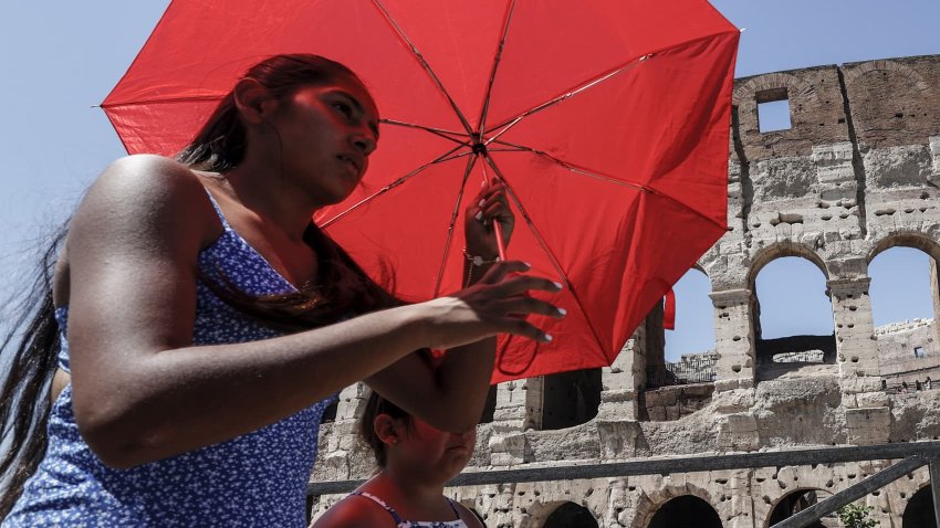 A woman uses an umbrella to protect herself from the sun as she passes past the Colosseum during an intensely hot day in Rome, Italy, on July 11, 2024. 