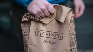 A customer holds a bag of food outside of a Chipotle restaurant in New York on Jan. 12, 2024.