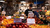 A worker arranges peaches at a fruit stand in the Pike Place Market in Seattle, Washington, US, on Thursday, July 4, 2024. 