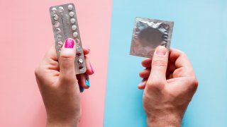 woman holds birth control pills, man holds condom