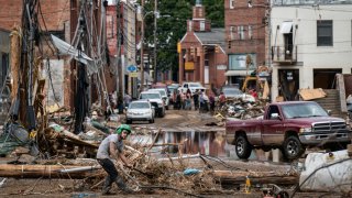 Workers, community members, and business owners clean up debris in the aftermath of Hurricane Helene in Marshall, North Carolina on Monday, Sept. 30, 2024.