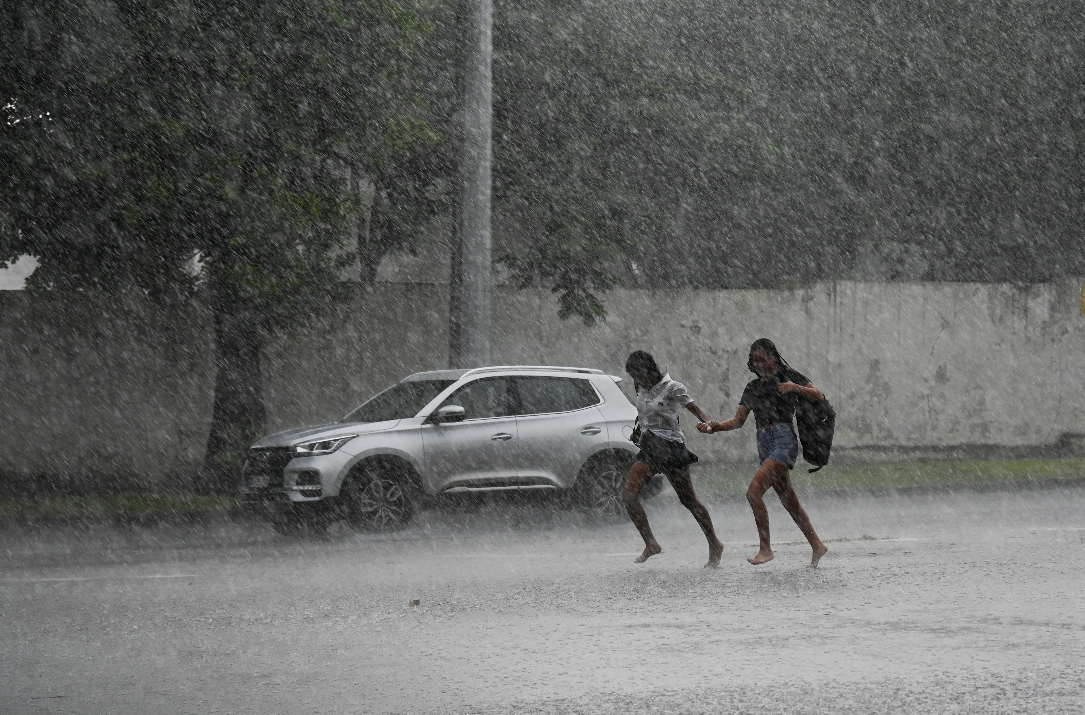 Young people run in torrential rain in Havana due to the passage of Hurricane Milton on October 9, 2024.