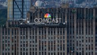People visit the Top of the Rock observation deck behind a Comcast corporate logo at the top of 30 Rock in Rockefeller Center seen from the Empire State Building on May 8, 2023, in New York City.