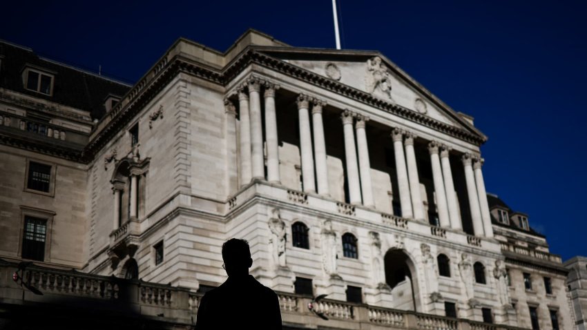 A pedestrian crosses the streets in front of The Bank of England illuminated by a ray of sunlight, in central London, on February 12, 2024.