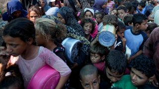 FILE – Palestinians line up for food distribution in Deir al-Balah, Gaza Strip, on Oct. 17, 2024.